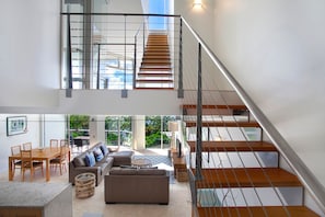 A modern interior with a staircase, a dining area, and a sofa.