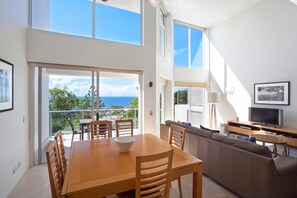 A modern interior with a dining area, a sofa, and a television.