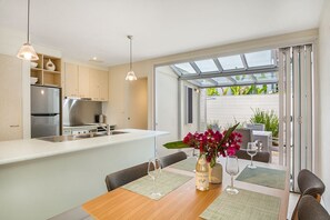 A modern kitchen with a large island, stainless steel appliances, and a dining area with a table set for two.