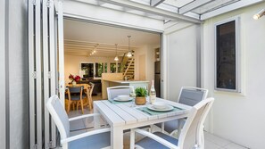 Enjoy meals in this spacious living area with a dining table for two, overlooking a balcony with a staircase.