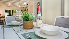 Enjoy a meal in style with a beautifully set dining table, complete with a potted plant and elegant wine.