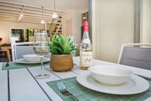 Una mesa de comedor con una botella de vino, una copa, un bol y un tenedor.