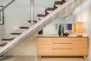 A modern staircase with glass railings and wooden steps, leading to a light-colored wall.