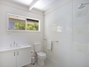 Een moderne badkamer met een wit wastafel, toilet en douche.