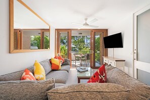 A modern living room with a sofa, television, and a view of the outdoors. - Little Cove Lodge 5 Park Road 24 (Noosa Heads)