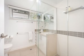 Un bagno moderno con box doccia in vetro, un water, un lavandino e un porta asciugamani.