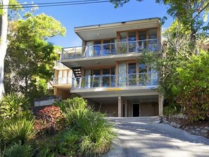 A two-story building with a balcony, a garage, and a stone wall.