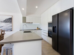 A modern kitchen with a large island, stainless steel appliances, and a view of the sea.