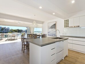 A modern kitchen with a central island, white cabinetry, and a view of the outdoors.
