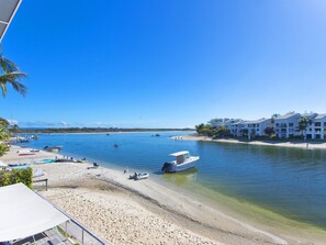 A beach with boats, a clear blue sky, and a building with balconies.