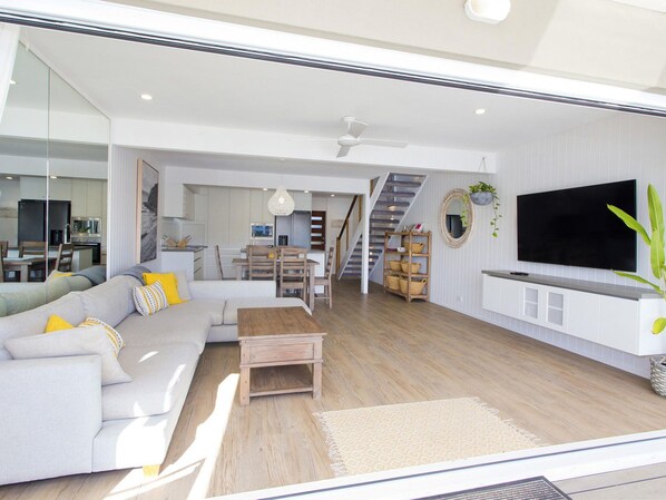 A modern living room with a sofa, coffee table, and a TV mounted on the wall.