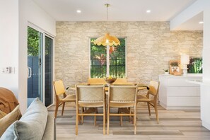 A dining area with a stone wall, a table with chairs, and a hanging light fixture.