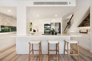 A modern kitchen with a central island, bar stools, and a staircase.