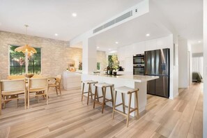Una cucina moderna con isola centrale, sgabelli da bar e zona pranzo con mobili in legno.