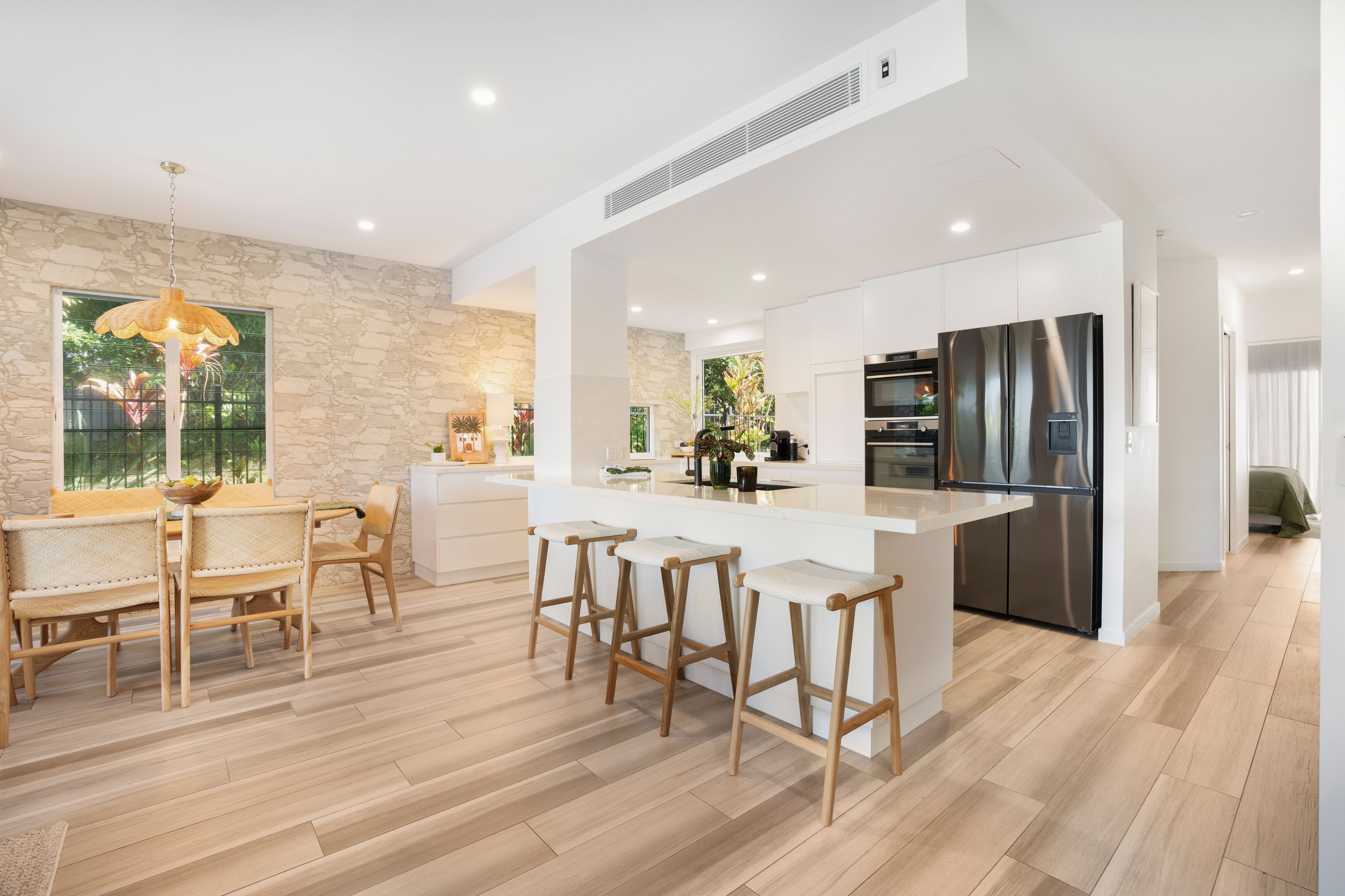 A modern kitchen with a central island, stainless steel appliances, and a stone accent wall.