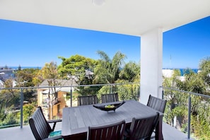 Un balcón con mesa y sillas, con vistas a una zona residencial y al mar.