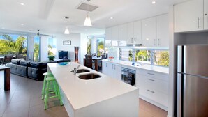 A modern kitchen with a central island, stainless steel appliances, and large windows.