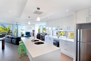 A modern kitchen with a central island, stainless steel appliances, and large windows. - Alpha On Elanda - Sunshine Beach Haven (Sunshine Beach)