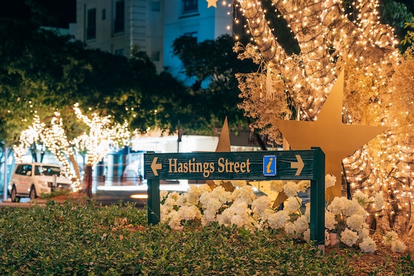 Una señal de calle para Hastings Street con flechas direccionales, rodeada de luces decorativas y flores blancas.