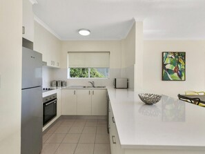 A modern kitchen with white cabinetry, a built-in oven, and a large island with a bowl.