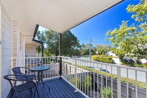 A covered outdoor area with a table and chairs, a brick wall, and a view of a street with a sign.