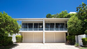 A two-story building with a flat roof, large garage doors, and a balcony with railings. - Dolphins 2 Alderly Terrace 36 (Noosa Heads)