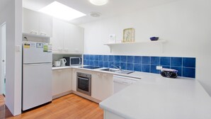 A modern kitchen with white cabinets, a microwave, an oven, and a dishwasher. - Dolphins 2 Alderly Terrace 36 (Noosa Heads)