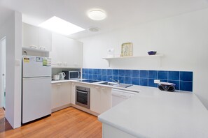 Una cocina moderna con armarios blancos, un microondas, un horno y un lavavajillas.