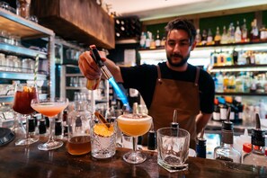 A bartender preparing drinks behind a bar with various bottles and glasses.