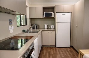A compact kitchen with a stove, sink, microwave, and refrigerator. - Costa Del Sol 2 Park Road 22 (Noosa Heads)