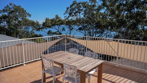 A terrace with a table and chairs, a white railing, and a view of trees and a body of water. - Costa Del Sol 3 Park Road 22 (Noosa Heads)