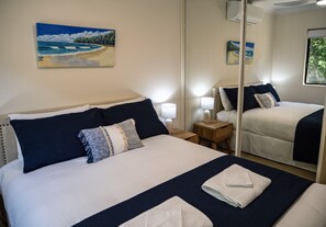 Une chambre d’hôtel avec un lit, des tables de chevet, des lampes, un miroir et un tableau au mur.