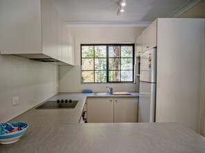 A compact kitchen with a window, a sink, a stove, and a refrigerator.