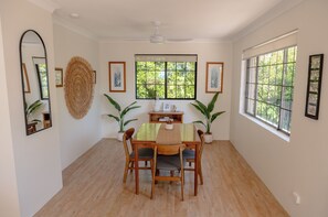 Un'area pranzo con tavolo in legno, sedie e ventilatore a soffitto.