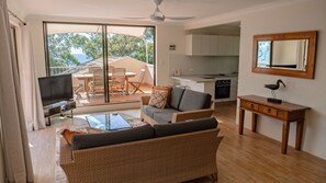 A living room with a sofa, TV, and dining area with chairs and a table.