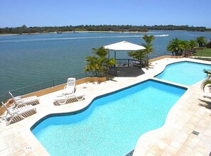 Une piscine dotée de chaises longues et d’un belvédère, avec vue sur une étendue d’eau.