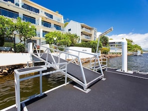 Un hotel moderno con embarcadero, mobiliario exterior y vista despejada al agua.