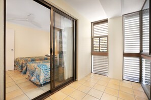 A room with a bed, a sliding glass door, and a window with blinds.