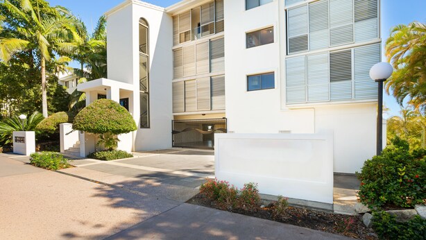 A modern building with a flat roof, large windows, and a gated entrance.