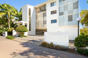 A modern building with a flat roof, large windows, and a gated entrance.