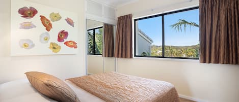 Una camera da letto con un letto, una finestra con tende e un quadro floreale al muro.