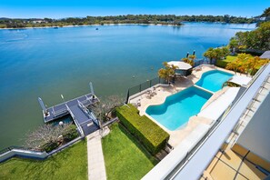 A residential property with a swimming pool, a dock, and a view of a large body of water.
