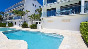 A modern hotel with a swimming pool, multiple balconies, and a clear blue sky. - Aqua Linea 3 Noosa Parade 82 (Noosa Heads)
