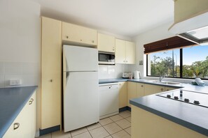 A kitchen with a refrigerator, microwave, and stove.