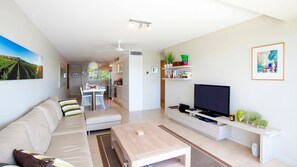 Relax in this stylish living room with a large flat-screen TV, comfortable sofa, and dining area.