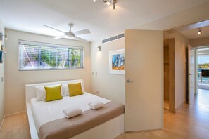 Ein modernes Hotelzimmer mit Bett, Deckenventilator, Kunstwerken und Blick durch das Fenster.