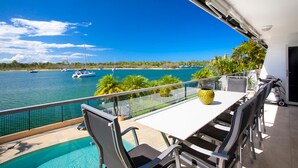 Ein Balkon mit Pool, Gartenmöbeln und Blick auf das Meer mit Booten.