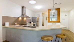 Una cucina moderna con isola centrale, elettrodomestici in acciaio inossidabile e sgabelli in legno.