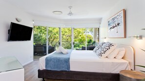 A modern bedroom with a bed, a flat-screen TV, and a balcony with glass doors.