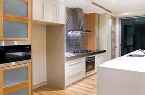 A modern kitchen with wooden cabinets, a stainless steel range, and a tiled backsplash.